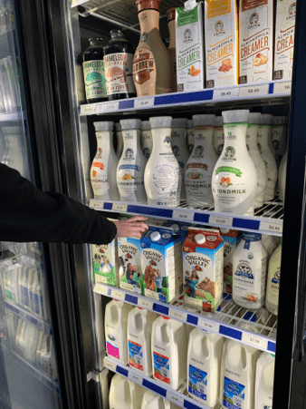 A customer reaches for milk at Royal Blue Grocery in Highland Park Village.