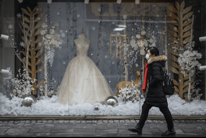 A woman in China walks past a wedding shop in a deserted shopping district. Photo credit: Getty Images