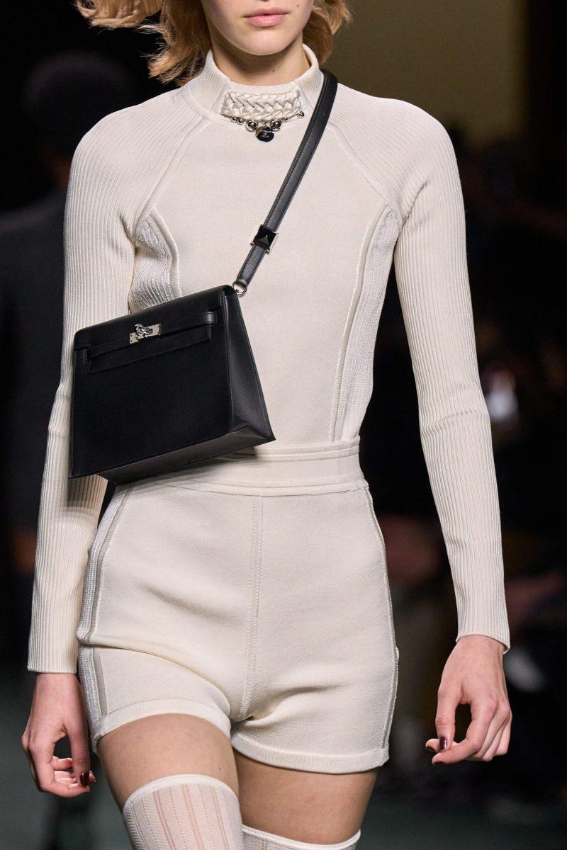 This shortened strap is a modern take on the Kelly crossbody, reminiscent of the newer belt bag trend worn as a short crossbody. The classic Kelly silhouette remains with the buckle closure and silver hardware. Photo credit: Vogue